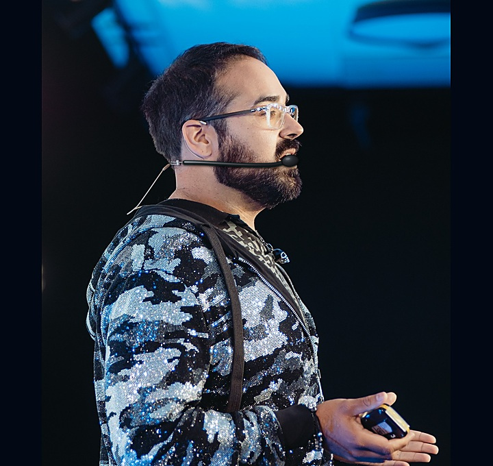 George speaking on stage with headset microphone